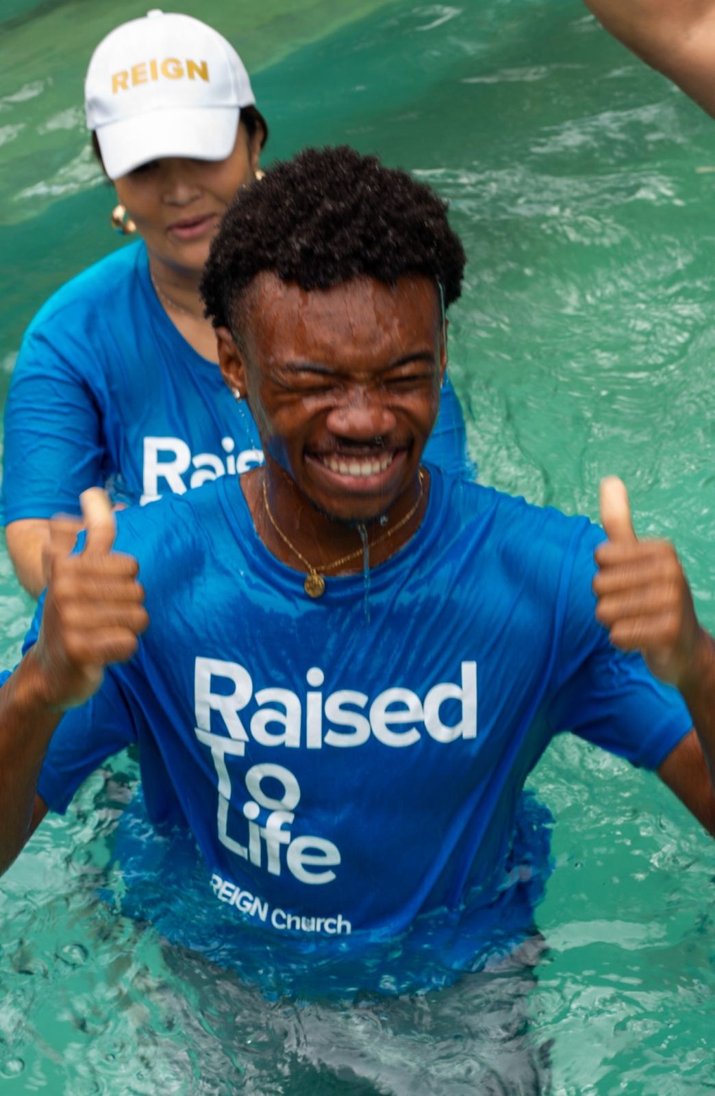 Freshly baptised believer smiling with a thumbs up beside the REIGN Church baptism pool