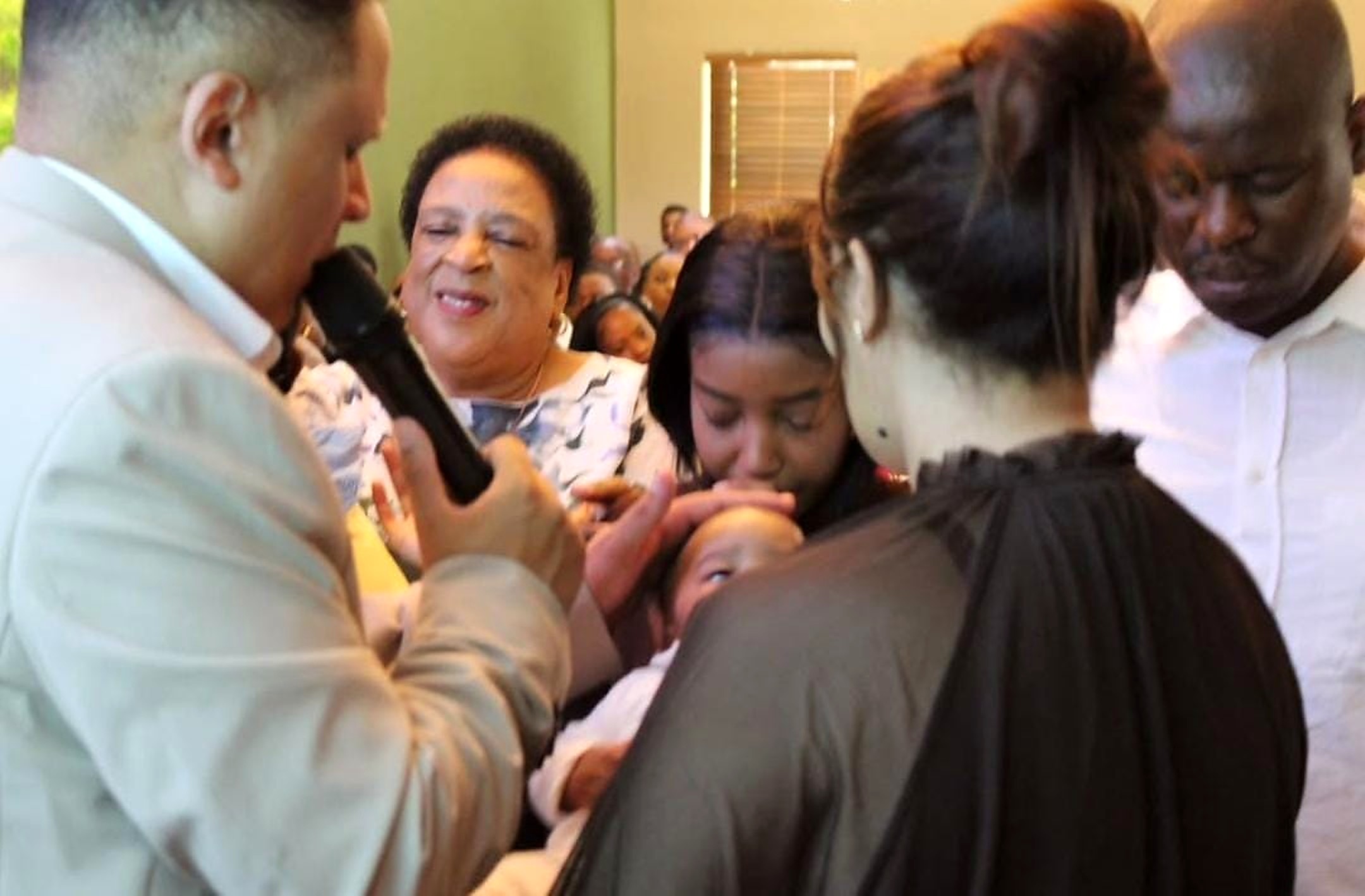 Parents dedicating their baby at REIGN Church Bloemfontein while Pastor Ian prays a blessing